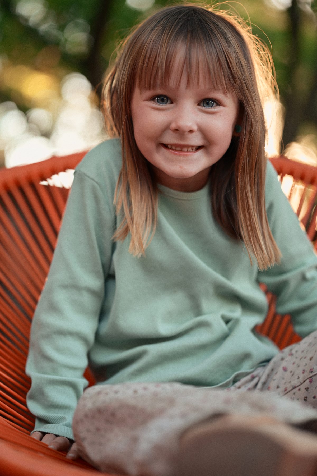 Girl sitting in red chair at golden hour
