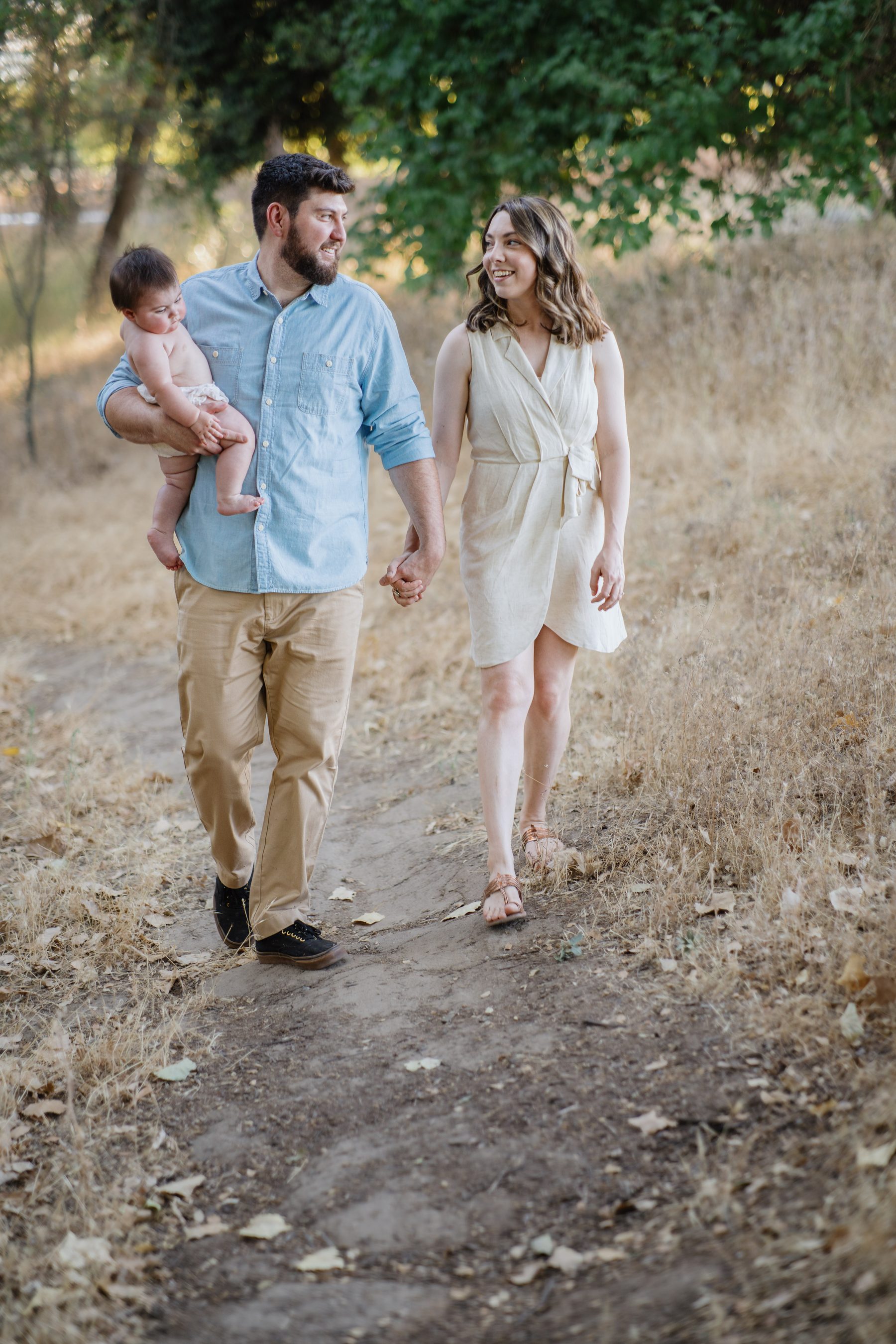 Father carrying his baby while walking hand in hand with his wife